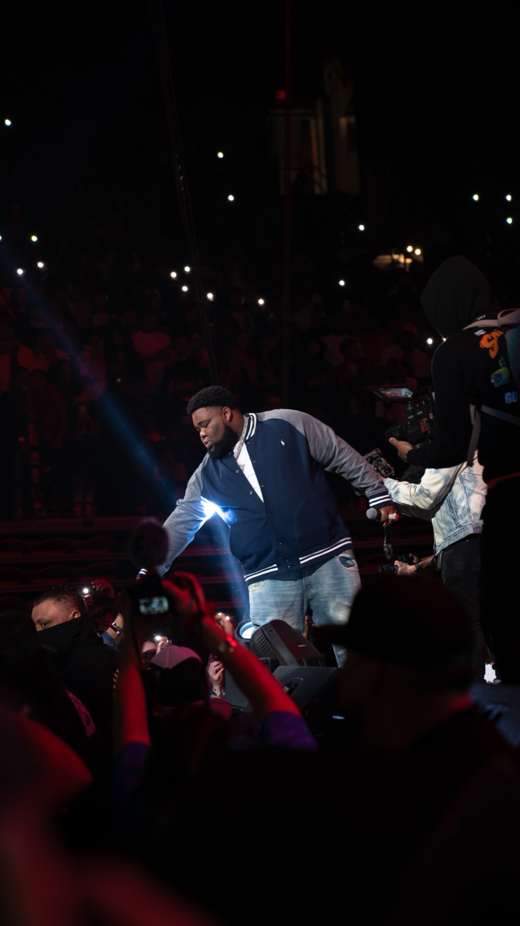 Performer in a varsity jacket commanding an arena stage